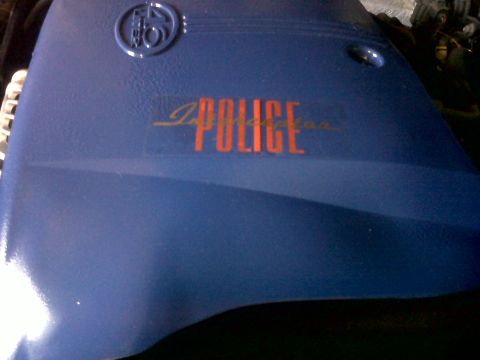 1999 Ford Crown Victoria - Close-up of a blue interior car part with 'POLICE' lettering and a circular emblem.