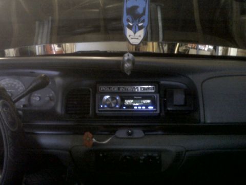 1999 Ford Crown Victoria - The interior of a 1999 Ford Crown Victoria shows the dashboard with a police interceptor badge and aftermarket stereo.