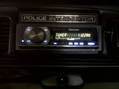 1999 Ford Crown Victoria - Interior view of a Police Interceptor badge and a Pioneer car stereo unit.
