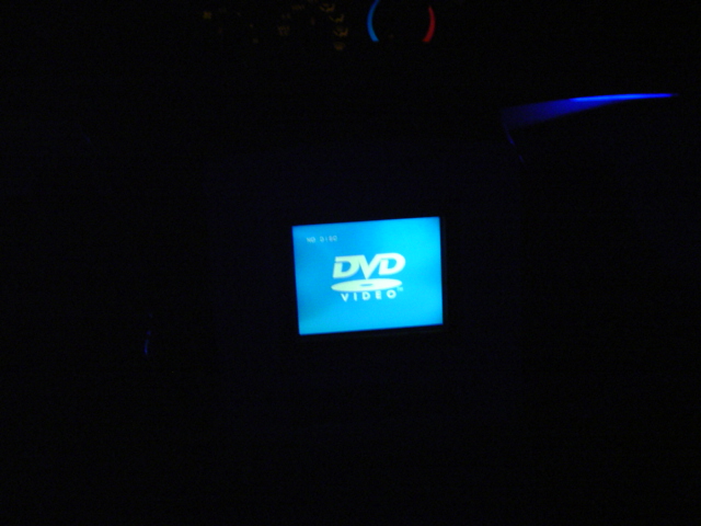 Dark interior with a glowing blue DVD Video screen and a blue light strip