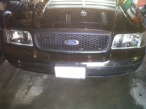 1999 Ford Crown Victoria - Front view of a black Ford Crown Victoria, showing the grille and headlights.