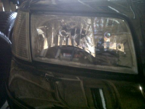 1999 Ford Crown Victoria - A close-up view of a vehicle's front headlight assembly and surrounding body panel.