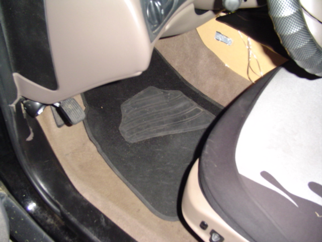 Interior view of driver's side floor with pedals and floor mat