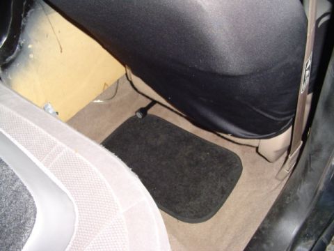 1999 Ford Taurus - The passenger side floor area of a vehicle, showing a black floor mat over tan carpet.
