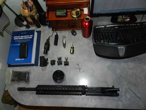 1996 Ford Bronco - Desk setup with firearm components and related accessories, including a book on long-range shooting.