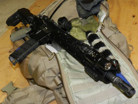 1996 Ford Bronco - An assault rifle with various tactical accessories is placed on top of a camouflage backpack.