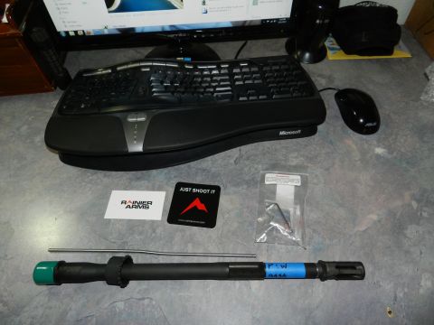 1996 Ford Bronco - A collection of firearm components and computer accessories are laid out on a desk surface.