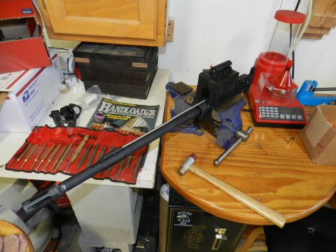 1996 Ford Bronco - A workbench is set up with tools for gunsmithing, including a vise holding a barrel and a reloading scale.