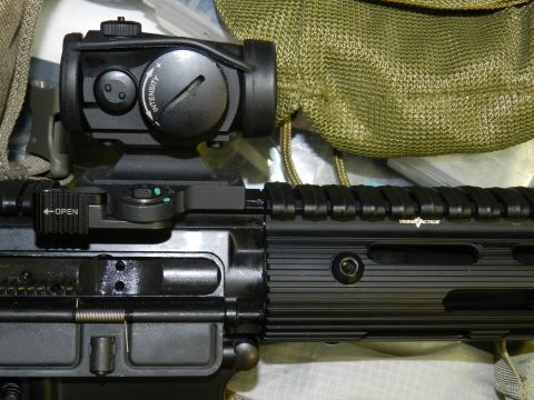 1996 Ford Bronco - Close-up view of a rifle's upper receiver with a mounted red dot sight and an "OPEN" lever visible.