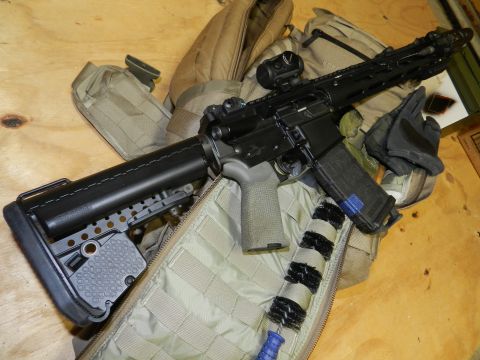 1996 Ford Bronco - An AR-15 style rifle is laid out with accessories including a red dot sight, extended magazine, and cleaning brush.
