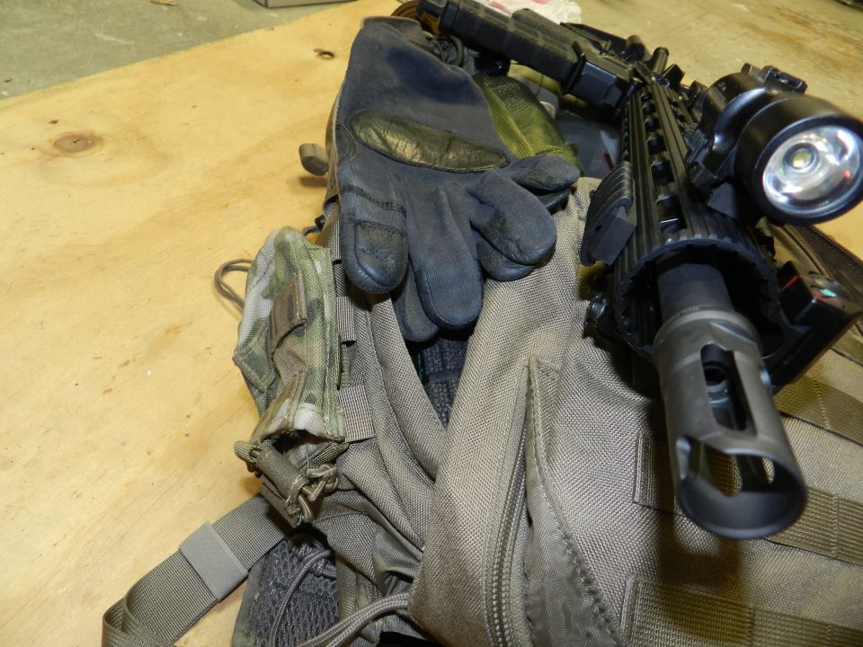 Tactical gloves and rifle barrel with flashlight mounted on a backpack