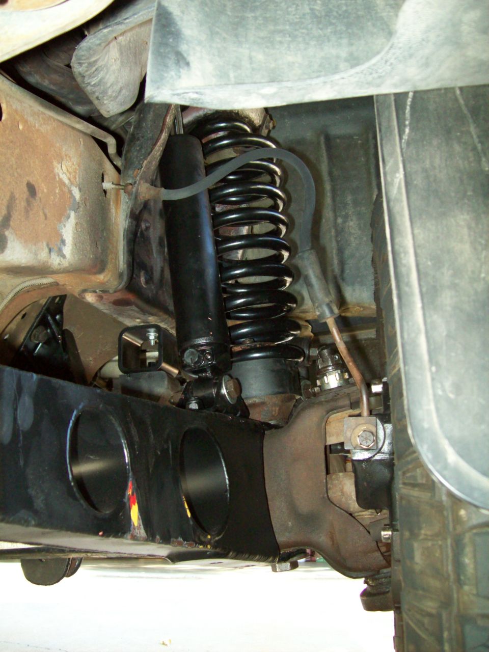 Close-up of a black coil spring and shock absorber assembly on a truck's suspension