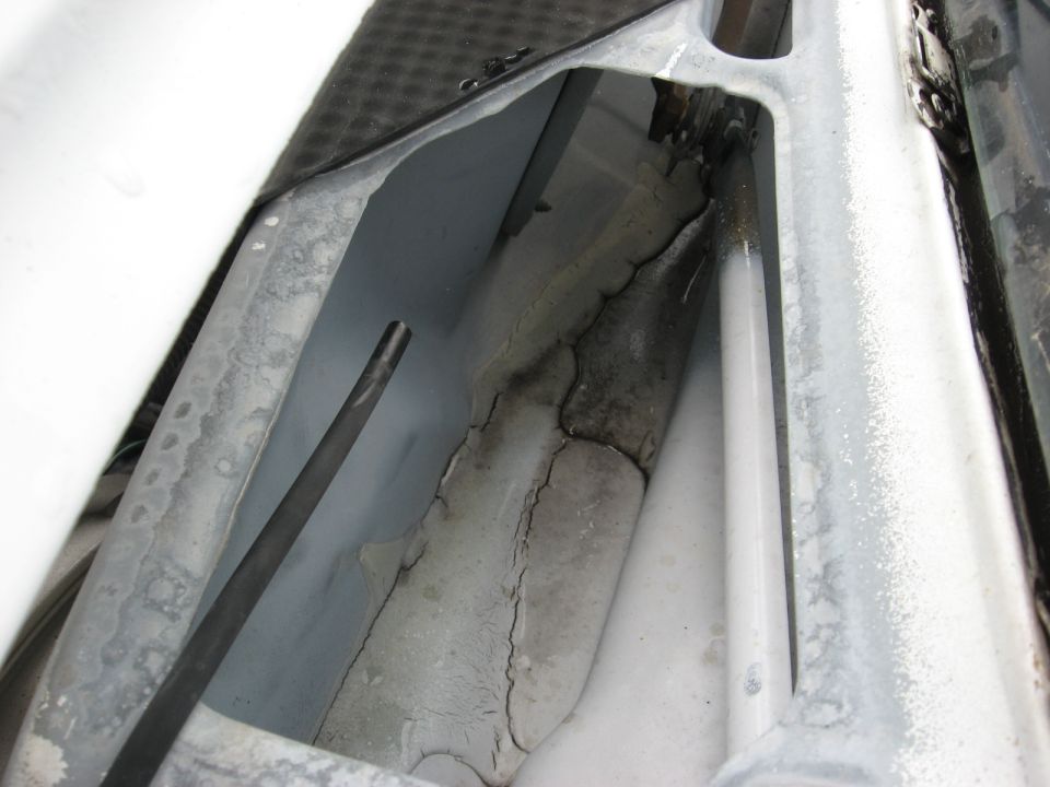 Close-up of cracked plastic trim and metal structure inside a vehicle