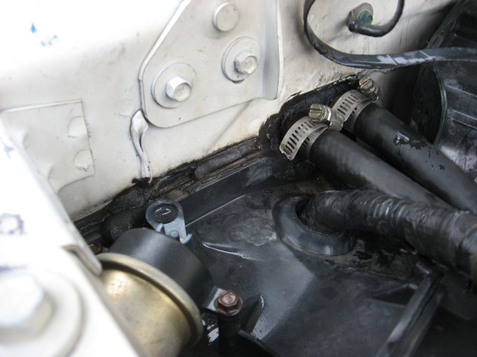 Close-up of engine bay showing rubber hoses secured with clamps, black sealant, and some metal components