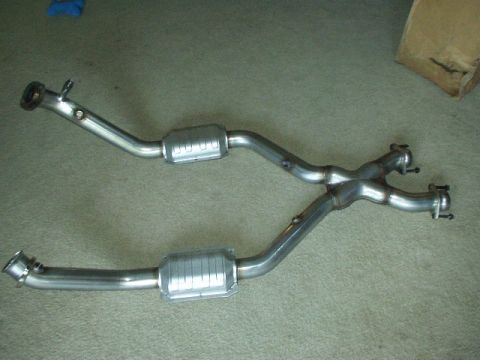 1998 Ford Crown Victoria - stainless steel dual exhaust X-pipe assembly with two catalytic converters, laid out on carpet.