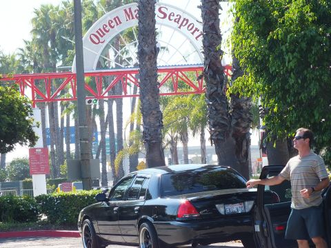 2003 Ford Crown Victoria - Man stands by a black sedan beneath the arched Queen Mary Seaport entrance sign