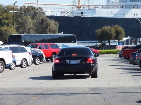 2003 Ford Crown Victoria - Rear of a lowered black sedan facing the moored Queen Mary ocean liner and a bus
