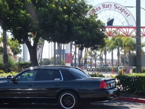 2003 Ford Crown Victoria - Dark sedan with decklid spoiler under the seaport arch, ship funnels visible behind