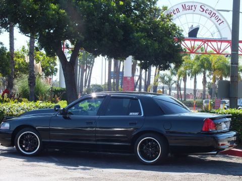 2003 Ford Crown Victoria - Black full-size sedan with window decal parked broadside under the seaport sign