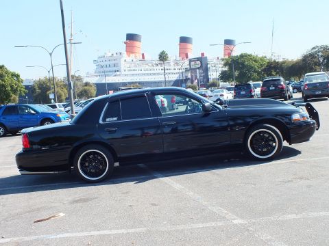 2003 Ford Crown Victoria - Lowered black full-size sedan on whitewall tires with the moored liner and funnels behind