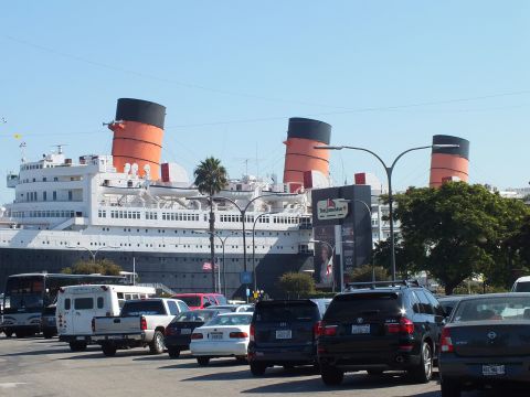 2003 Ford Crown Victoria - white three-funnel liner looms over a full parking lot of cars, trucks and an SUV in the foreground.