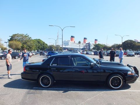 2003 Ford Crown Victoria - Side profile of a lowered black Crown Victoria on whitewall tires with the Queen Mary behind.