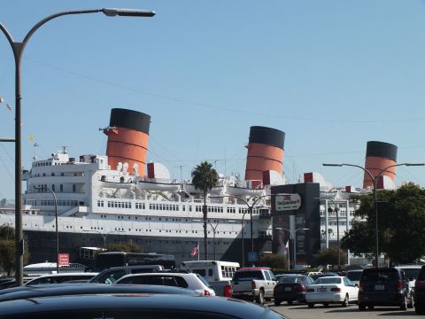 2003 Ford Crown Victoria - retired Queen Mary ocean liner and its three funnels rise above a busy parking lot.