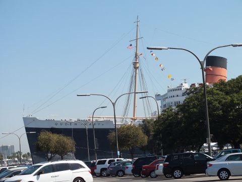 2003 Ford Crown Victoria - historic Queen Mary ship docked beyond a full parking lot, nautical flags strung from its mast.