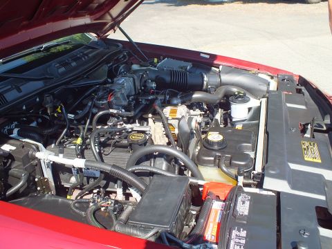 2003 Ford Crown Victoria - Under-hood view of a maroon Ford sedan with the modular V8, battery and intake plumbing exposed.