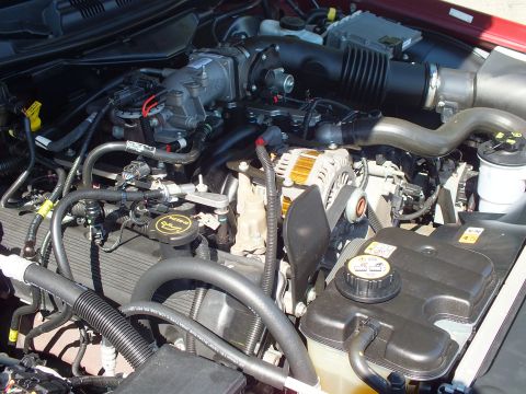 2003 Ford Crown Victoria - Overhead shot of a red Ford sedan engine bay featuring the V8, coolant tank and air intake routing.