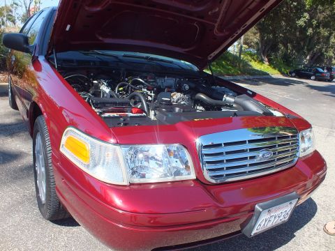 2003 Ford Crown Victoria - Maroon Ford Crown Victoria sedan parked with hood raised, chrome grille and Ford oval badge in front.
