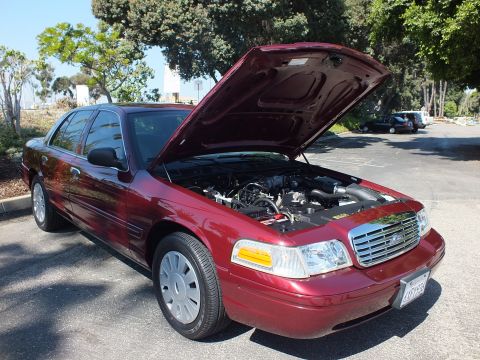 2003 Ford Crown Victoria - Dark red Ford Crown Victoria sedan shown front three-quarter with hood up and chrome Ford grille.