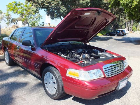 2003 Ford Crown Victoria - Front three-quarter of a maroon Ford Crown Victoria with hood open in a tree-lined parking lot.