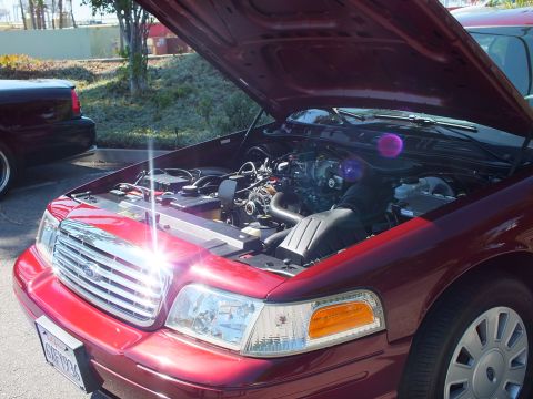 2003 Ford Crown Victoria - Maroon Ford Crown Victoria photographed with hood up, V8 engine and chrome grille catching the sun.