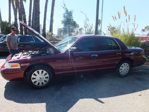 2003 Ford Crown Victoria - Side view of a maroon Ford Crown Victoria with raised hood; a man in a cap stands nearby.