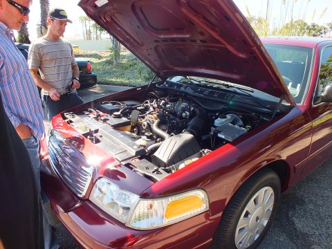 2003 Ford Crown Victoria - Two men look over the V8 engine of a dark red Ford Crown Victoria with its hood raised.