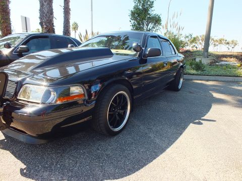 2003 Ford Crown Victoria - Front quarter view of a glossy black Crown Victoria with billet grille on black rims.