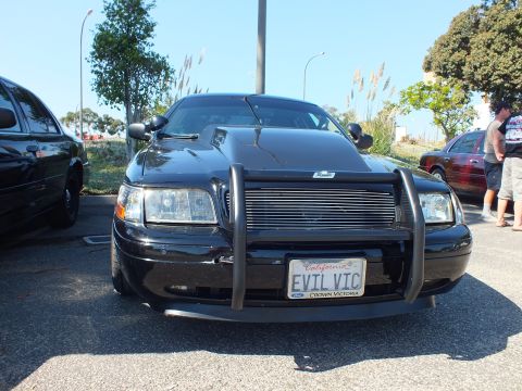 2003 Ford Crown Victoria - Front of a black Crown Victoria with billet grille and EVIL VIC plate, people nearby.