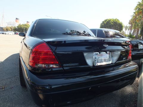 2003 Ford Crown Victoria - Tail view of a black Crown Victoria Police Interceptor with the Queen Mary behind it.