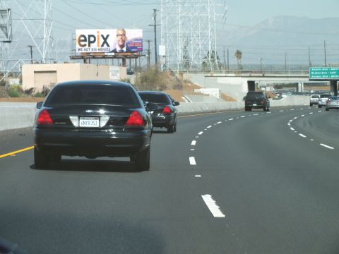 2003 Ford Crown Victoria - Two black Crown Victorias cruise a curving freeway near an Epix billboard.