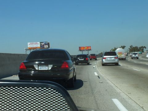 2003 Ford Crown Victoria - Rear view of a black Crown Victoria in highway traffic past roadside billboards