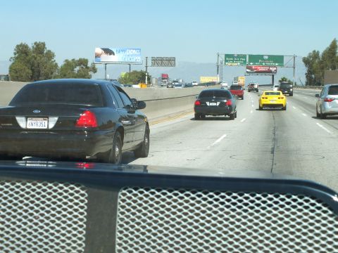 2003 Ford Crown Victoria - Highway lanes with a black sedan, dark coupe, and a yellow car ahead