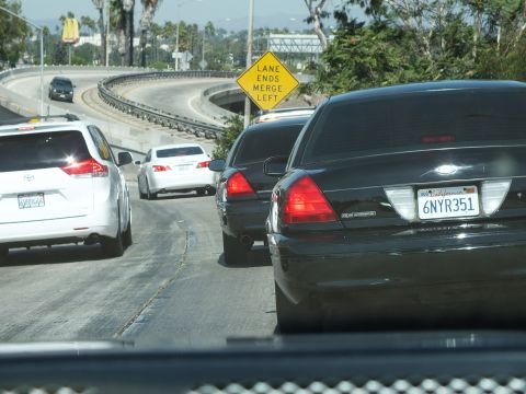 2003 Ford Crown Victoria - Stopped traffic on a curving ramp with a yellow merge warning sign