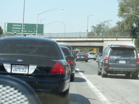 2003 Ford Crown Victoria - Black sedan and SUV in slow freeway traffic past a green Indiana St sign