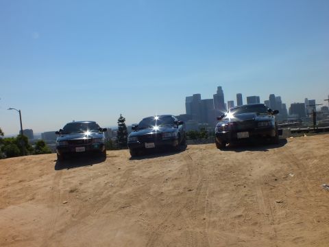 2003 Ford Crown Victoria - Front view of three black sedans parked on a hill with downtown behind