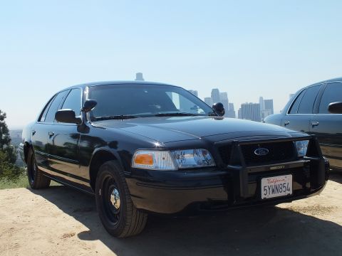 2003 Ford Crown Victoria - Blacked-out Crown Victoria with black steel wheels and grille guard, plate 5YWN854, downtown towers in haze