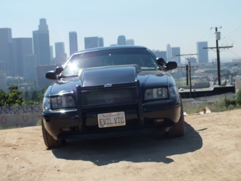 2003 Ford Crown Victoria - Front of a black Crown Victoria fitted with a brush guard and billet grille; EVIL VIC California plate.