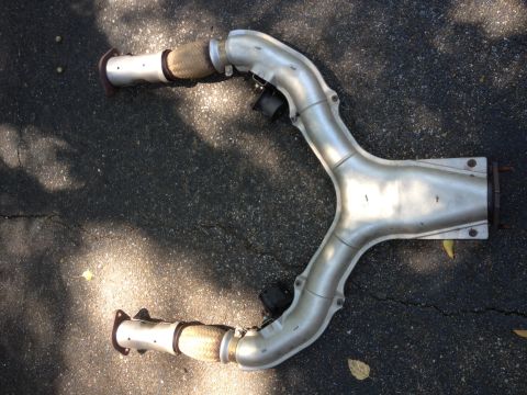 1996 Ford Bronco - An exhaust pipe with flexible connectors is shown laid out on asphalt.
