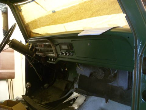 1967 Ford F-250 - The interior of a green 1967 Ford F-250 truck is shown, with the dashboard and steering wheel visible.