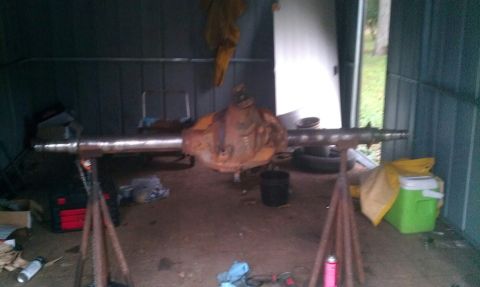 1995 Ford Bronco - Rear axle assembly on jack stands in a shed, with various tools and items in the background.
